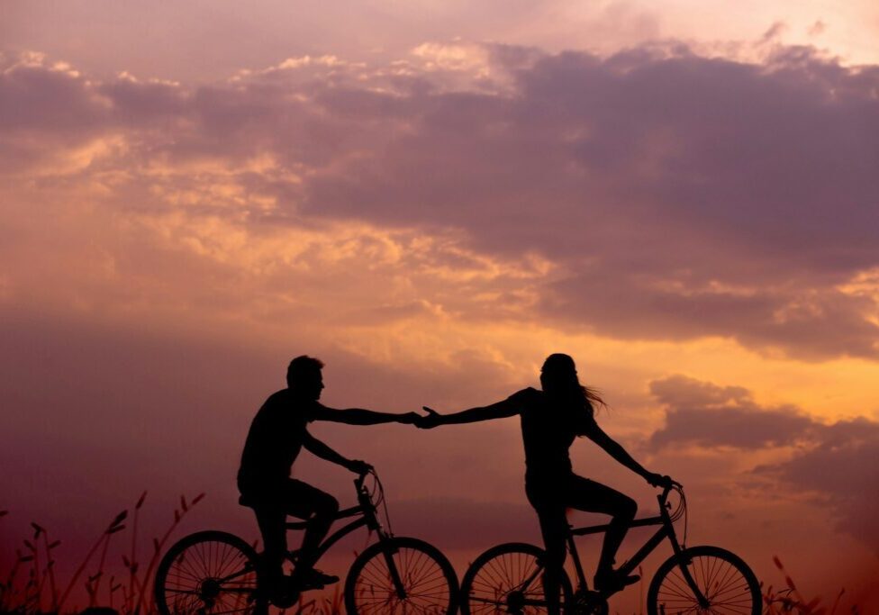 a couple biking and reaching for each other